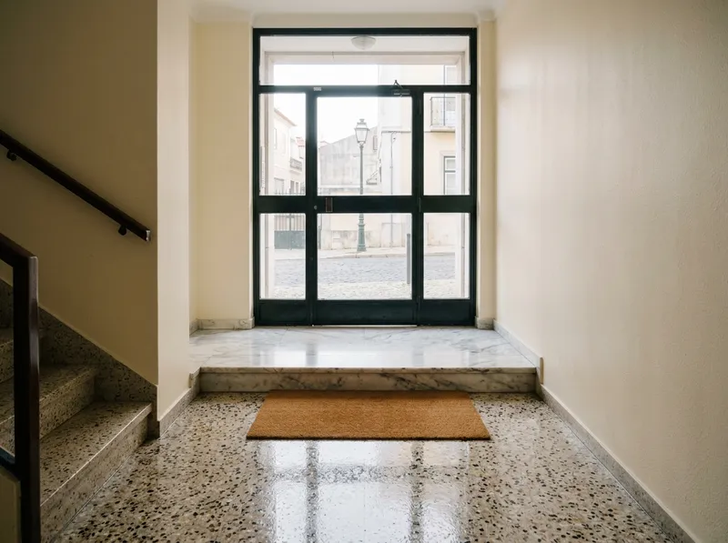 Hall de entrada em terrazzo com luz da manhã pela porta de vidro
